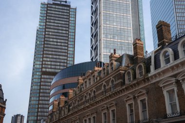 Bacalı geleneksel bir tuğla bina, Londra 'da berrak bir gökyüzünün altında silindirik ve ızgara desenli bir kule de dahil olmak üzere parlak gökdelenlerin aksine ayakta duruyor..