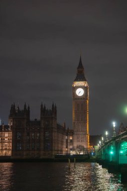 Big Ben saat kulesi ve Westminster Köprüsü gece karanlığında parlıyor. Thames Nehri, Londra 'nın tarihi mimarisinin ışıklarını yansıtır..