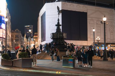 Geceleri Piccadilly Meydanı 'nda Shaftesbury Memorial Fountain, aydınlatılmış sokaklar, parlak reklamlar ve Londra' daki grup insan yer alıyor..