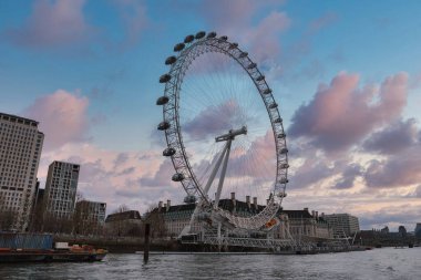 Londra 'nın gözü Thames nehri boyunca parlak pembe ve mavi bir gökyüzü ile duruyor. Modern ve tarihi binalar bu şehir manzarasının dönüm noktasını çevrelemektedir..
