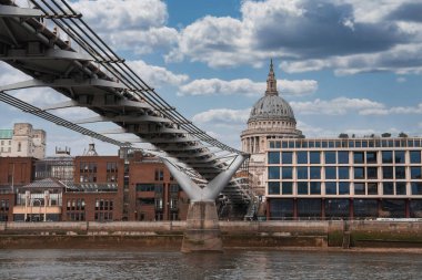 Milenyum Köprüsü, Londra 'daki Thames Nehri boyunca uzanır ve arka planda modern ve geleneksel binalar tarafından çerçevelenmiş St. Paul Katedrali' nin kubbesi bulunur..