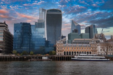 Walkie Talkie ve Scalpel binalarının, Thames Nehri 'nin, kenetlenmiş bir teknenin ve ön planda tarihi bir binanın yer aldığı Londra' nın ufuk çizgisi..