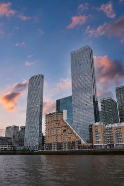 Günbatımında Thames Nehri, Newfoundland binası ve pembe turuncu gökyüzünün altındaki Kanarya Rıhtımı 'ndaki One Canada Meydanı ile Londra' nın ufuk çizgisinin görüntüsü..