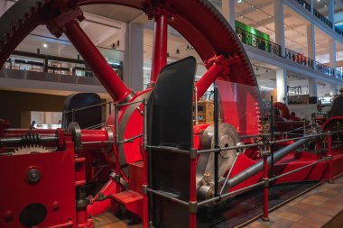 Karmaşık dişli ve pistonlu büyük bir kırmızı buhar motoru modern mimari ile çevrili Londra 'daki Bilim Müzesi' nde sergileniyordu..