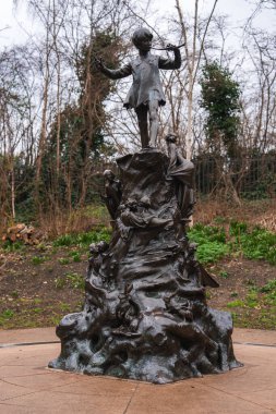 Londra, Kensington Bahçeleri 'ndeki Bronz Peter Pan heykeli, Peter' ı ağaçların tepesinde periler ve orman yaratıklarının çıplak ağaçlara yaslandığını gösteriyor..