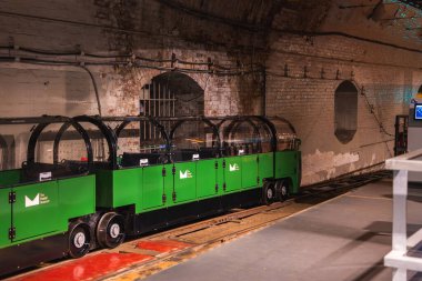 Şeffaf kubbeli çatıları olan yeşil bir minyatür tren Londra 'daki tarihi posta hattının bir parçası olan tuğla kaplı bir yeraltı tünelinde duruyor..