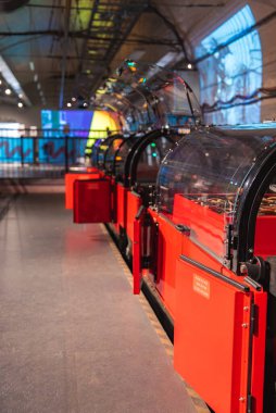 Müze ortamında şeffaf kubbeli kırmızı kapsüller. Kirişleri ve renkli ışıklandırması olan endüstriyel mimari.