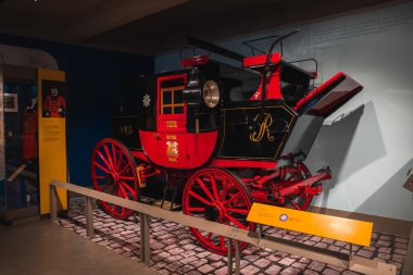 Altın rengi posta arabası ve Bristol 'dan Londra' ya giden yol üzerinde parke döşenmiş bilgi panelleri olan siyah ve kırmızı bir Kraliyet posta arabası..