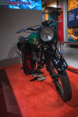 Londra müzesinde sergilenen, yeşil ve siyah renkli, kraliyet tacı amblemi ve plakası GGY 525 olan klasik bir Postane motosikleti..