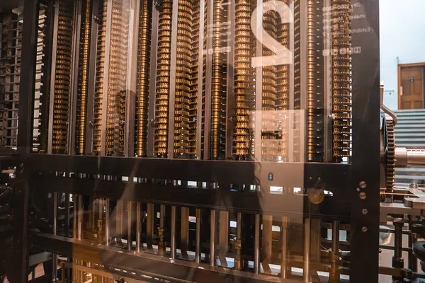 Pirinç dişli ve kollu bir mekanik bilgisayar cihazı, muhtemelen Londra 'da bir müze ortamında cam bir muhafazada sergileniyor..