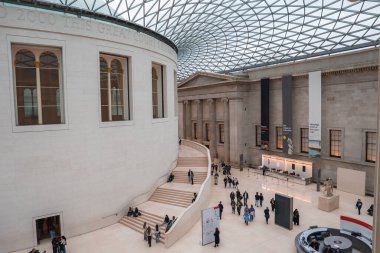Londra 'daki British Museum' un Büyük Mahkemesi 'nde cam ve çelik bir çatı, dairesel okuma odası, ziyaretçiler ve neoklasik mimari yer alıyor..