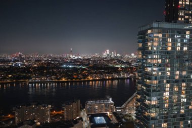 Londra 'da geceleri gökdelenler ve şehir ışıklarını yansıtan Thames Nehri' nin yer aldığı gökdelenler aydınlandı. Ön planda yüksek bir bina var..