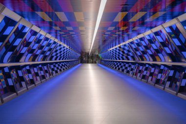 Londra 'da canlı bir dama tahtası deseni, yumuşak mavi ışık ve cam bir çıkışa giden simetrik geometrik tasarımı olan modern bir yaya tüneli..
