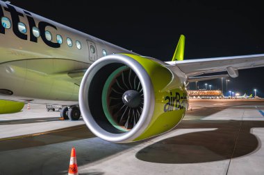 Geceleri pistte park halindeki bir hava aracı. Parlak yeşil bir motoru, görünür bir markası, yanan bir terminali var..