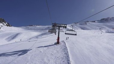 Kar İsviçre 'nin Zermatt kentindeki yamaçları kaplarken, kayak asansörleri hareket ediyor ve kayakçılar alçalıyordu. Eskrim ve işaretler manzaralı bir dağlık alanda çizgiler çiziyor..