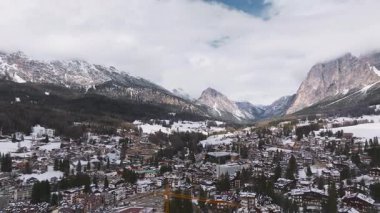 Cortina ve Ampezzo 'nun alp mimarisi, karla kaplı manzaraları, ve Dolomite zirveleri, kademeli olarak hareketli.