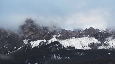 Cortina yakınlarındaki engebeli Dolomite dağlarının havadan görünüşü. Karla kaplı tepeler, sis ve alçak bulutlar. Yavaş pan ışığı ve gölge etkileşimini vurgular.