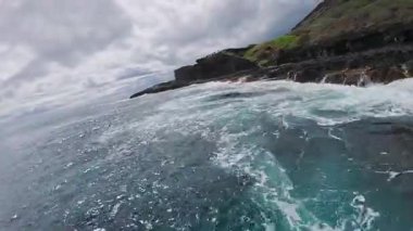 Oahu veya Kauai, Hawaii 'deki altın kumsal volkanik kayalar ve yeşilliklerle sınırlıdır. İki kişi dalgalarla kıyı boyunca yavaşça yürüyor..