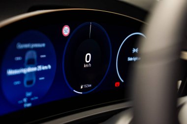 Lüks bir arabanın dijital gösterge panelinin 0 km / h 'lik hız göstergesi, lastik basıncı grafiği, yan ışık uyarısı ve hız limiti işareti gösteren yakın görüntüsü.