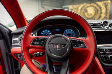Bentley Bentayga iç tasarımı, kırmızı deri bir direksiyon, logo, karbon fiber torpido aksanı ve dijital göstergeler gösteriyor..