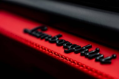 Lamborghini 'nin parlak siyah harfli logosu parlak kırmızı deride ayrıntılı dikişlerle sergileniyor, lüks otomotiv işçiliği sergiliyor..