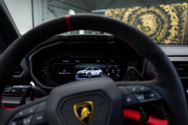 Lamborghini 'nin içini kapatın. Direksiyonu logo, dijital gösterge paneli ile lüks bir galeride Urus ve kırmızı aksanları gösteriyor..