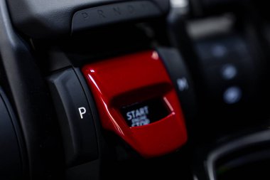 PRND işaretli dişli seçiciyi gösteren lüks bir arabanın iç görüntüsünü kapat ve parlak bir tasarımla kırmızı kaplamalı motoru çalıştır düğmesi.