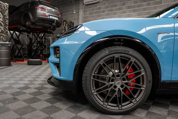 Kırmızı fren kalibreli ve Bridgestone lastikli mavi bir Lamborghini Urus 'un ön bölümü, bir otomotiv atölyesinde kareli bir zemine park edilmiş..