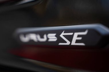 Lamborghini Urus 'taki Urus S rozetinin yakın görüntüsü, parlak, karanlık bir yüzey üzerinde sergileniyor ve rozeti vurguluyor..