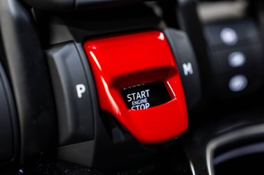 Kırmızı kapak altındaki Lamborghini Urus motor başlatma düğmesinin ayrıntılı görünümü, vites göstergeleriyle çevrili siyah ve metalik aksanlar.