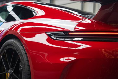 Kırmızı bir 2025 Porsche 911 GT3922 'nin arka görüntüsü kapalı, LED arka lambası, parlak boyası ve amblemli siyah alaşımlı tekerleği gösteriyor..