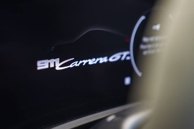 911 Carrera GTS metnini bir araba siluetiyle gösteren Porsche dijital ekranının yakın görüntüsü, vurgu için koyu bir arkaplan üzerine kurulmuş.