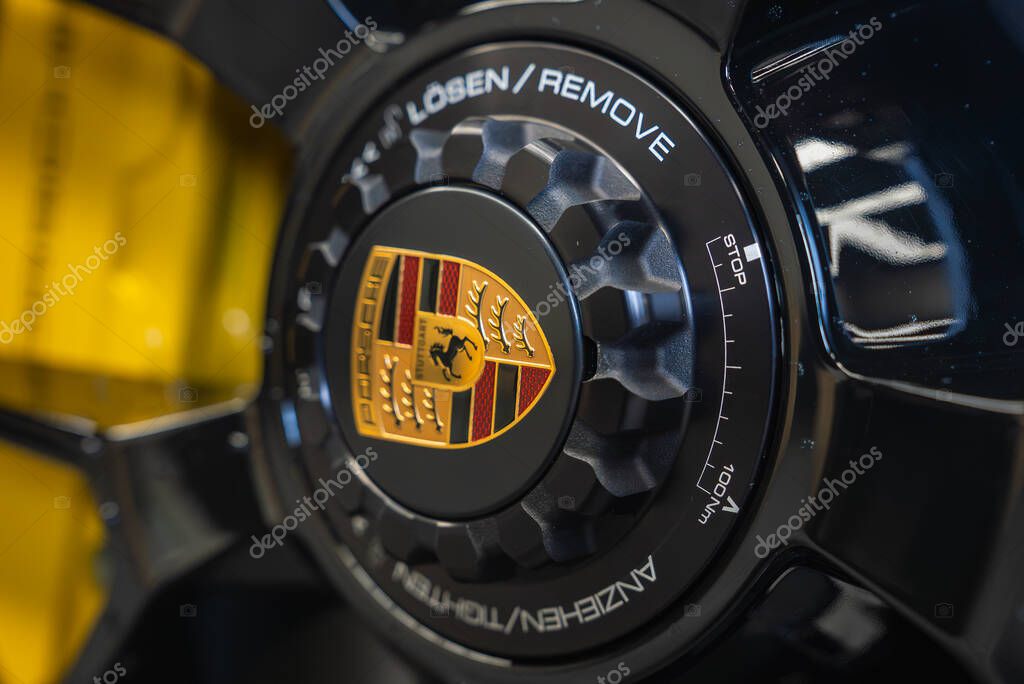 Detailed view of the center lock wheel hub on a 2025 Porsche 911 GT3, featuring the Porsche crest, etched specifications, and a blurred yellow background.