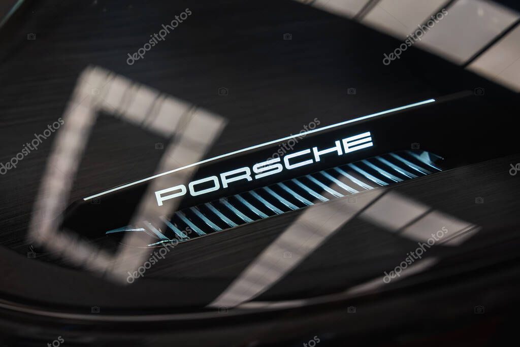 Detailed view of the illuminated Porsche logo on the rear of the 2025 Porsche 911 GT3 922, showcasing sharp lines, a vented grille, and reflective lighting.