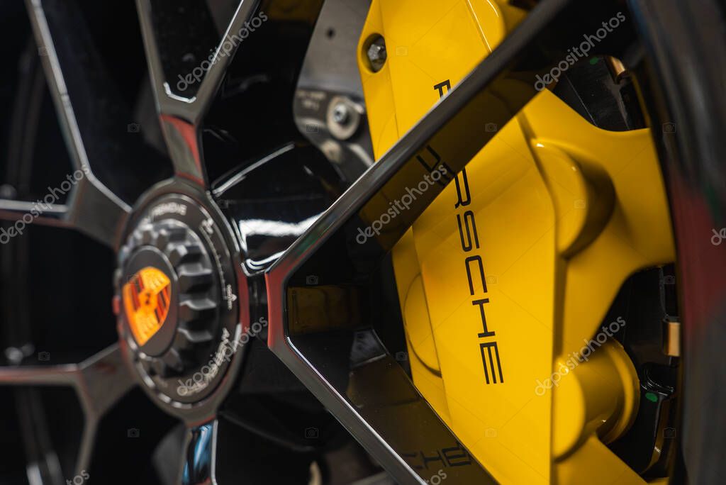 Detailed view of a black alloy wheel with a yellow brake caliper featuring the Porsche logo, showcasing precision engineering and luxury design.