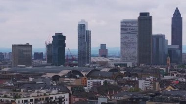Frankfurt, Almanya 'nın hava manzarası, Messeturm, Tower 185, modern gökdelenler, geleneksel çatılar ve bulutlu bir gökyüzünün altındaki uzak tepeler.