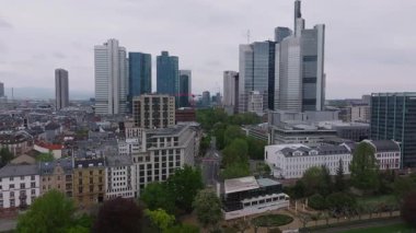 Frankfurt, Almanya 'nın hava manzarası, Commerzbank Tower ve Main Tower gibi modern gökdelenler, ağaç kaplı caddeler ve bulutlu bir gökyüzü.