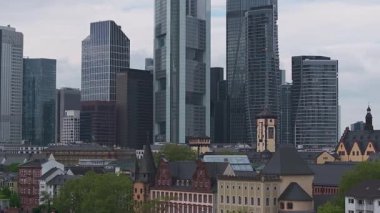 Frankfurt, Almanya 'nın hava manzarası, modern gökdelenleri, ana kuleyi, tarihi bir kiliseyi, ana nehri ve çevresindeki yeşillikleri gösteriyor..