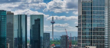 Frankfurt, Almanya, arka planda Europaturm, cam cepheli modern gökdelenler, inşaat vinçleri ve parçalı bulutlu gökyüzü.
