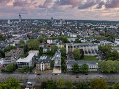 Frankfurt, Almanya 'nın hava görüntüleri, orta büyüklükteki binaları, yeşillikleri ve bulutlu bir gökyüzünün altında kendine özgü bir gökdelenle yoğun bir kentsel alanı gösteriyor..