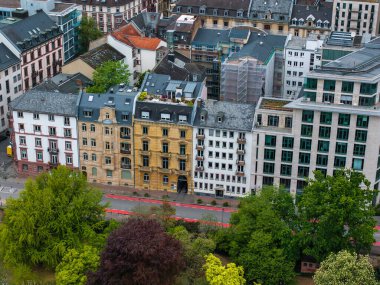 Frankfurt, Almanya 'nın canlı bir hava manzarası, tarihi cephelerin, modern binaların, ağaç sıralı sokakların ve ön planda yemyeşil yeşilliklerin sergilendiği.