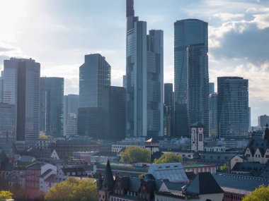 Ticari Kule de dahil olmak üzere modern gökdelenler, parçalı bulutlu bir gökyüzü altında Frankfurt, Almanya 'daki geleneksel Avrupa mimarisinin üzerinde yükseliyor..