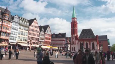 Frankfurt, Almanya 'daki Romerberg Meydanı' nda yarım keresteli binalar, Eski St. Nicholas Kilisesi ve canlı atmosferin keyfini çıkaran insanlar yer alıyor..