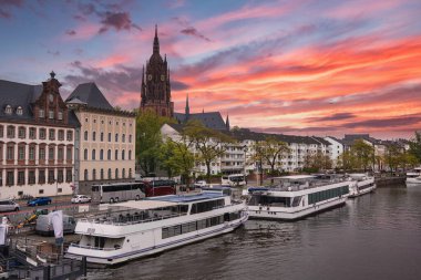 Frankfurt, Almanya 'da nehir kenarı manzarası, Gotik Frankfurt Katedrali, modern nehir tekneleri, tarihi binalar ve bulutlu gökyüzü.