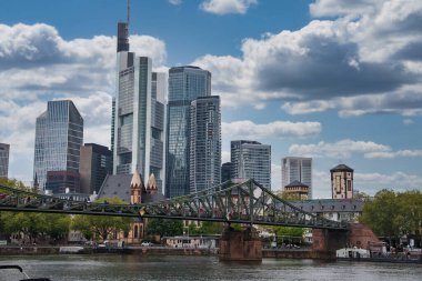 Frankfurt, Almanya 'nın Skyline' ında Commerzbank Kulesi, modern gökdelenler, Eiserner Steg köprüsü ve yemyeşil ağaçlar yer alıyor..