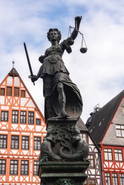 Frankfurt 'taki Romerberg Meydanı' ndaki Adalet Pınarı heykeli. Bayan Adalet ve arka planda yarı ahşap binalar..
