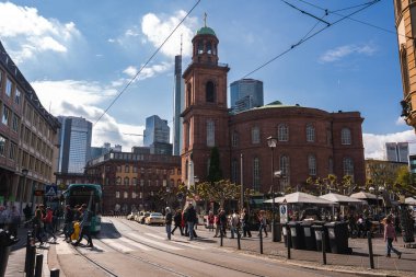Frankfurt 'ta St. Paul Kilisesi, modern gökdelenler, yayalar, tramvay, açık hava koltukları ve açık mavi gökyüzü..