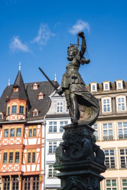 Frankfurt 'taki Romerberg Meydanı' ndaki Adalet Çeşmesi 'nde geleneksel yarı ahşap binalar tarafından çerçevelenmiş pullar ve kılıçla Adalet Anıtı yer alıyor..
