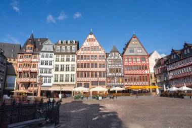 Frankfurt, Almanya 'daki Romerberg Meydanı' nda sembolik yarı ahşap binalar, kaldırım taşları, açık hava koltukları ve açık mavi bir gökyüzü bulunmaktadır..