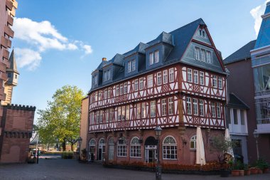 Frankfurt, Almanya 'da kırmızı-beyaz iskeleti olan yarı keresteli bina, bir kaldırım taşı kare, ağaçlar ve karışık mimariyle çevrili..